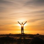 Christian standing in prayer at sunrise — overcoming fear with faith.