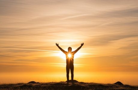 Christian standing in prayer at sunrise — overcoming fear with faith.